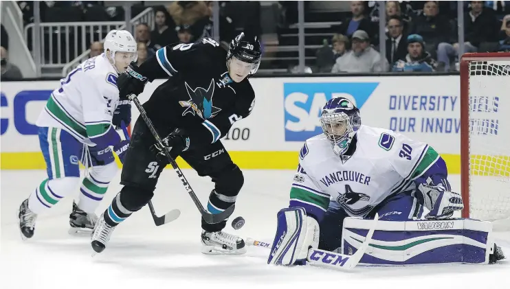  ?? — THE ASSOCIATED PRESS ?? San Jose Shark Marcus Sorensen eyes the puck next to Vancouver Canucks goalie Ryan Miller during the first period on Thursday night in San Jose, Calif.