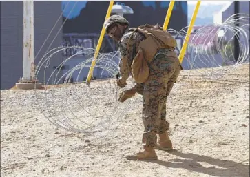  ?? John Gibbins San Diego Union-Tribune ?? A MARINE CORPS engineer from Camp Pendleton puts up razor wire east of the San Ysidro Port of Entry in San Diego on Friday. So far some 1,300 troops have been assigned to support operations along the border.