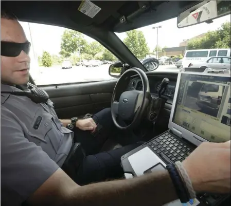  ?? AP PHOTO/PABLO MARTINEZ MONSIVAIS ?? In this July 16, 2013, file photo, Officer Dennis Vafier, of the Alexandria Police Department, uses a laptop in his squad car to scan vehicle license plates during his patrols in Alexandria, Va.