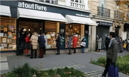  ?? Photograph: Charles Platiau/Reuters ?? People queue to collect from a bookshop in Paris. A strict lockdown has been in place in France since 30 October.