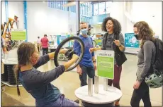  ?? (Courtesy photo) ?? Adults discover the rotational force of physics in the gyroscope seat experiment in “GEAR UP: The Science of Bikes.”