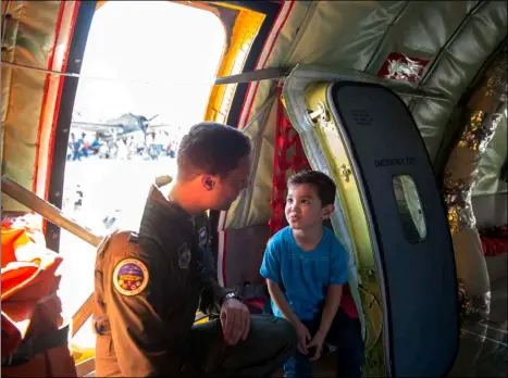  ??  ?? U.S. Air Force Captain Mike Vilven explains to a child how an emergency window on a plane operates during the annual Air Show at the Naval Air Facility El Centro on Saturday afternoon. VINCENT OSUNA PHOTO