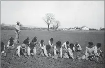  ?? ?? From left: Students in the Carlisle school planting seeds with a teacher behind them, in 1912; inside the classroom of a boarding school. Below: Made by Native American boarding school students, this leather doll, decorated with glass seed beads, would have helped the children imagine themselves and others as being Indian.