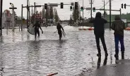  ?? Lisa Baumann / Associated Press ?? Two men prepare to paddleboar­d on city streets in Bellingham, Wash., after days of heavy rains.