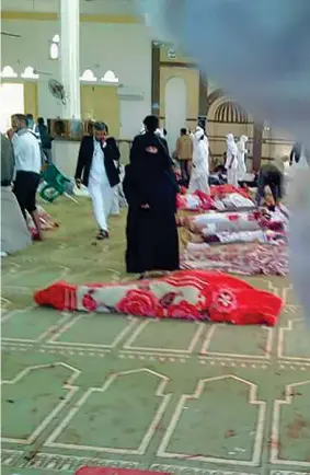  ??  ?? I fedeli della moschea radunati attorno alle vittime dell’attentato a Rawda, in Egitto