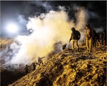  ??  ?? Central American migrants run away from tear gas thrown by the US border patrol after they tried to cross from Tijuana to San Diego in the US, as seen from Tijuana, Baja California state. — AFP photo