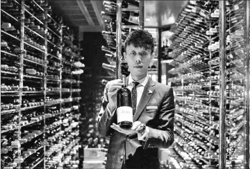  ??  ?? Assistant sommelier Felix Ho Ho Yua posing with a 2014 bottle of Ao Yun red wine at the Robuchon restaurant wine cellar in Hong Kong.