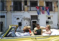  ??  ?? HAVANA: In this March 20, 2016 file photo, tourists ride in a classic American car past a balcony decorated with Cuban and US flags in Havana. Slow growth during a surge of interest in foreign investment and the greatest tourism boom in decades attests...