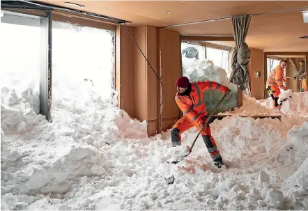  ?? AP ?? Workers help to clear snow from inside the Hotel Saentis in Schwaegalp, Switzerlan­d after it was hit by an avalanche during the severe winter weather gripping Europe.