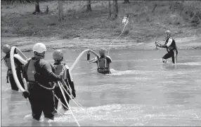  ?? Michael Burchfiel/Siloam Sunday ?? Fire/EMS crews took turns completing different drills, including this strainer drill, which crews had to cross the river to set up.