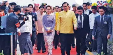  ?? Agence France-presse ?? ↑ Aung San Suu Kyi (centre left) and Thai PM Chan-o-cha (centre right) walk together during the opening ceremony of a bridge in Myawaddy, Kayin State, on Tuesday.