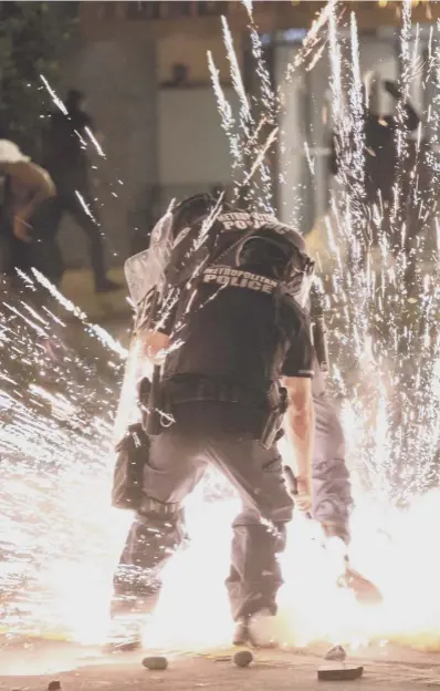  ??  ?? 0 A firecracke­r thrown by protesters explodes beside police near the White House in Washington DC