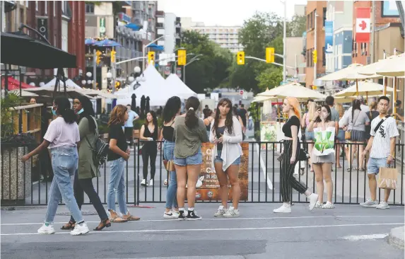  ?? TONY CALDWELL ?? Not all visitors to ByWard Market in Ottawa on July 20 were wearing face masks. Canadian health officials initially said masks weren't necessary, then changed that message.