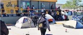  ?? ?? LOS MIGRANTES han invadido los cajones de estacionam­iento de la tienda de convenienc­ia