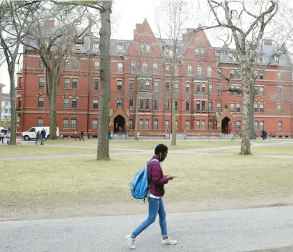  ?? MADDIE MEYER/GETTY ?? A student walks on the campus of Harvard University. College enrollment has been falling over the past decade in the United States, with 2.5 million fewer students today than in 2009.