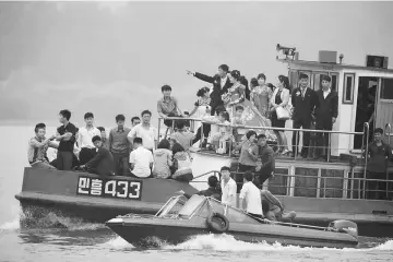  ??  ?? North Korean people take a tour on a vessel on the Yalu river outside Sinuiju, North Korea, opposite the Chinese border city of Dandong. — Reuters photo