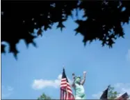  ?? DAVID GOLDMAN — THE ASSOCIATED PRESS ?? A woman dressed at the Statue of Liberty waves to the crowd while riding on a float in the Fourth of July parade in Marietta, Ga., Wednesday.