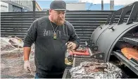  ?? JOHN KIRK-ANDERSON/
STUFF ?? Smokey T’s owner Tristin Anderson at work on the barbecue.