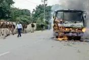  ??  ?? Police personnel walk past a city bus set ablaze by angry students of Allahabad Central University during a protest against the murder of a law student, in Allahabad on Monday PTI