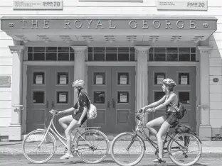  ?? PETER J. THOMPSON • NATIONAL POST/FILE ?? Cyclists ride past The Royal George Theatre in Niagara-On-The-Lake, home to the Shaw Festival, in June.