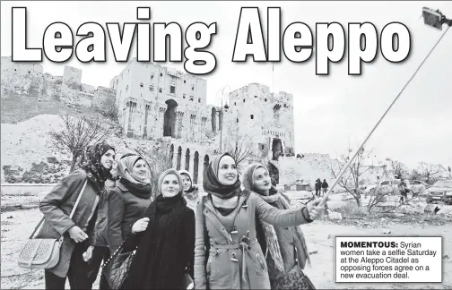  ??  ?? MOMENTOUS: Syrian women take a selfie Saturday at the Aleppo Citadel as opposing forces agree on a new evacuation deal.