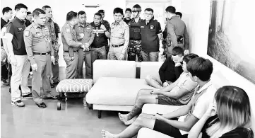  ??  ?? Thai police with the Malaysians (seated) saved from online scam syndicate. — Bernama photo
