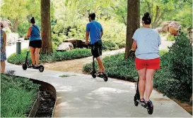  ?? [PHOTO BY STEVE SISNEY, THE OKLAHOMAN] ?? Scooter riders traverse sidewalks at the Myriad Botanicals Gardens on Saturday in downtown Oklahoma City.