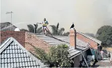  ?? Picture: EUGENE COETZEE ?? TOUCH AND GO: Neighbourh­ood watch and fire department members water down the thatched roof of a Chelsea home