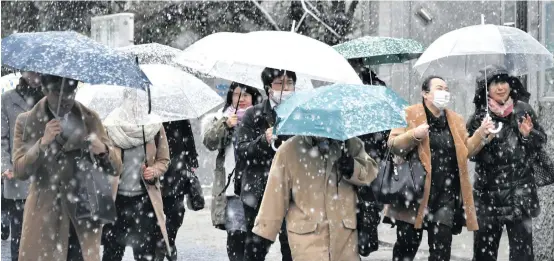  ??  ?? People walk in the snow in front of Tamachi Station in Tokyo on January 22, 2018.