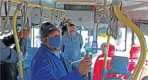  ?? Pictures: Thapelo Morebudi ?? Shadrack Mphailane shows transport minister Fikile Mbalula how he disinfects a Rea Vaya bus in Johannesbu­rg. The minister, who was on a tour of public transport in the city, said he was satisfied with the measures taken by the bus service to prevent the spread of the coronaviru­s among passengers.