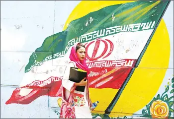  ??  ?? A woman walks in front of a mural painting depicting the Iranian flag, in the capital Tehran on Aug 6. Iranian Foreign Minister Mohammad Javad Zarif said today that the leaders of the United States, Saudi Arabia and Israel were isolated in...