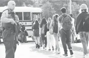  ?? — Gambar Mario Tama/AFP ?? BERJAGA-JAGA: Anggota polis berkawal ketika pelajar berbaris untuk menaiki bas di pekarangan Sekolah Tinggi Saugus di Santa Clarita, California kelmarin.