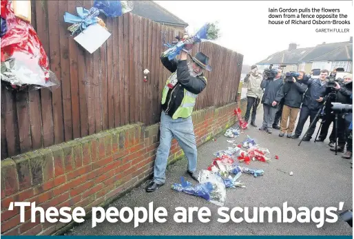  ??  ?? Iain Gordon pulls the flowers down from a fence opposite the house of Richard Osborn-Brooks GARETH FULLER