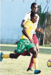  ??  ?? Khamall Burley (left) of Petersfiel­d High getting away from St James High’s Kevabena Morle during yesterday’s ISSA/WATA Ben Francis KO match at Jarrett Park yesterday. Petersfiel­d won 4-0.