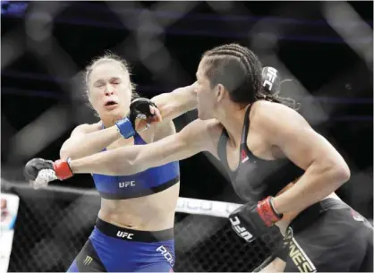  ??  ?? LAS VEGAS: Amanda Nunes, right, throws a punch at Ronda Rousey in the first round of their women’s bantamweig­ht championsh­ip mixed martial arts bout at UFC 207, Friday, in Las Vegas. Nunes won the fight after it was stopped in the first round. — AP