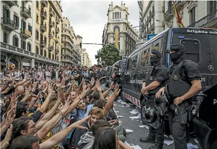  ?? PHOTO: REUTERS ?? Catalonian police officers surround the offices of the Spanish National Police in Barcelona as protesters gather outside yesterday following the disputed independen­ce referendum.