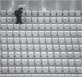  ?? CHRISTOPHE ENA AP ?? A spectator with an umbrella walks away after all matches of the French Open were canceled because rain. Two women’s and two men’s quarterfin­als were moved to Thursday.