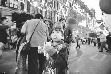  ??  ?? A boy eats a piece of traditiona­l ‘Rosca de Reyes’ (kings’ cake), at the Zocalo square in Mexico City on Epiphany’s eve. Mexico registered its highest annual inflation rate in more than 16 years in 2017, according to official data released, piling...