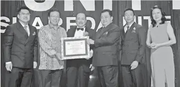  ??  ?? A.M. Ibnu (second left) receiving the award from Goh, witnessed by Hajiji. Seen at left is Kong.