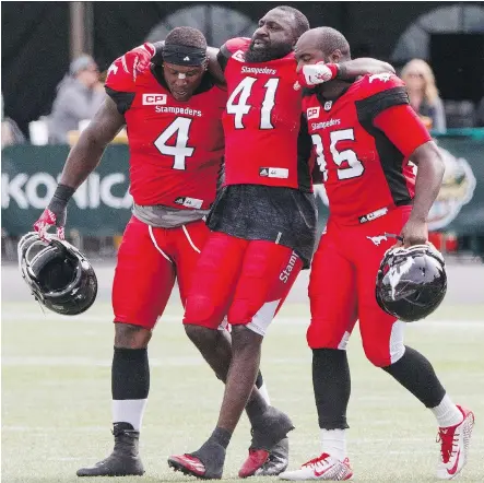  ?? AMBER BRACKEN/THE CANADIAN PRESS ?? Calgary Stampeders defensive end Cordarro Law, centre, was helped off by teammates Micah Johnson, left, and Ja’Gared Davis during Sunday’s CFL exhibition against the Edmonton Eskimos in Edmonton. Law suffered a fractured leg.