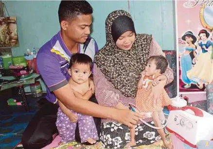  ?? [FOTO NIK ABDULLAH NIK OMAR/BH] ?? Suriati dan Mohamad Izuan bersama Nurul Damia Irdina (kanan) yang mengalami pelbagai komplikasi ketika ditemui di rumah mereka, di Kampung Kubang Batang, Tumpat.