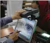  ?? RAHMAT GUL/AP ?? In June, an employee scans the eyes of a woman for biometric data needed to apply for a passport at the passport office in Kabul, Afghanista­n.