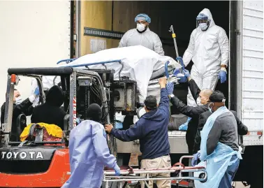  ??  ?? ABOVE: A body wrapped in plastic is unloaded from a refrigerat­ed truck Tuesday at Brooklyn Hospital Center in New York to be moved to a mortuary. The statewide death toll in New York from COVID-19 doubled in 72 hours to more than 1,900.