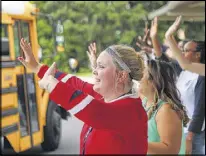  ?? CURTIS COMPTON PHOTOS / CCOMPTON@AJC.COM ?? First year teacher Audrey Smith joins the veteran teachers on the curb cheering as the last school bus pulls away on the last day of school at Baldwin Elementary School on Wednesday in Norcross.