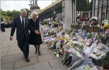  ?? YUI MOK — POOL PHOTO VIA AP ?? Britain’s King Charles III, left, and Camilla, the Queen Consort, look at floral tributes outside Buckingham Palace following Thursday’s death of Queen Elizabeth II, in London, on Friday. King Charles III, who spent much of his 73years preparing for the role, planned to meet with the prime minister and address a nation grieving the only British monarch most of the world had known. He takes the throne in an era of uncertaint­y for both his country and the monarchy itself.