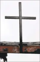  ??  ?? Fire reminder: A fire-damaged cross looks over the entryway at Cardinal Newman High School in Santa Rosa.