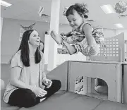  ??  ?? Nanny Lauren Lancaster watches 22-month-old Amelia Dzialo leap to a mat as children play and learn at Gymboree Play & Music in Norman.