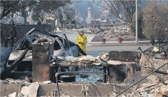  ?? Picture / AP ?? Cal Fire’s Kim Sone inspects the remains of homes in Santa Rosa destroyed by this week’s fires.