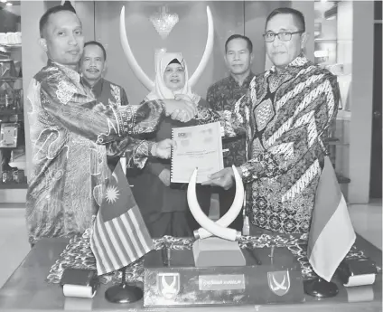  ??  ?? Salmi (left) and Denny exchange the MoU document, witnessed by Rubiah (centre), Bustaman (second left) and Widido.