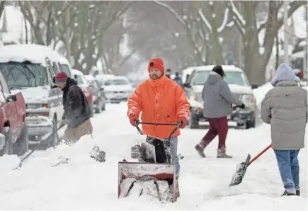  ?? MIKE DE SISTI / MILWAUKEE JOURNAL SENTINEL ?? Bob Drapp and his neighbors work together Monday to shovel South 28th Street just south of West Forest Home Avenue before the plow arrived.